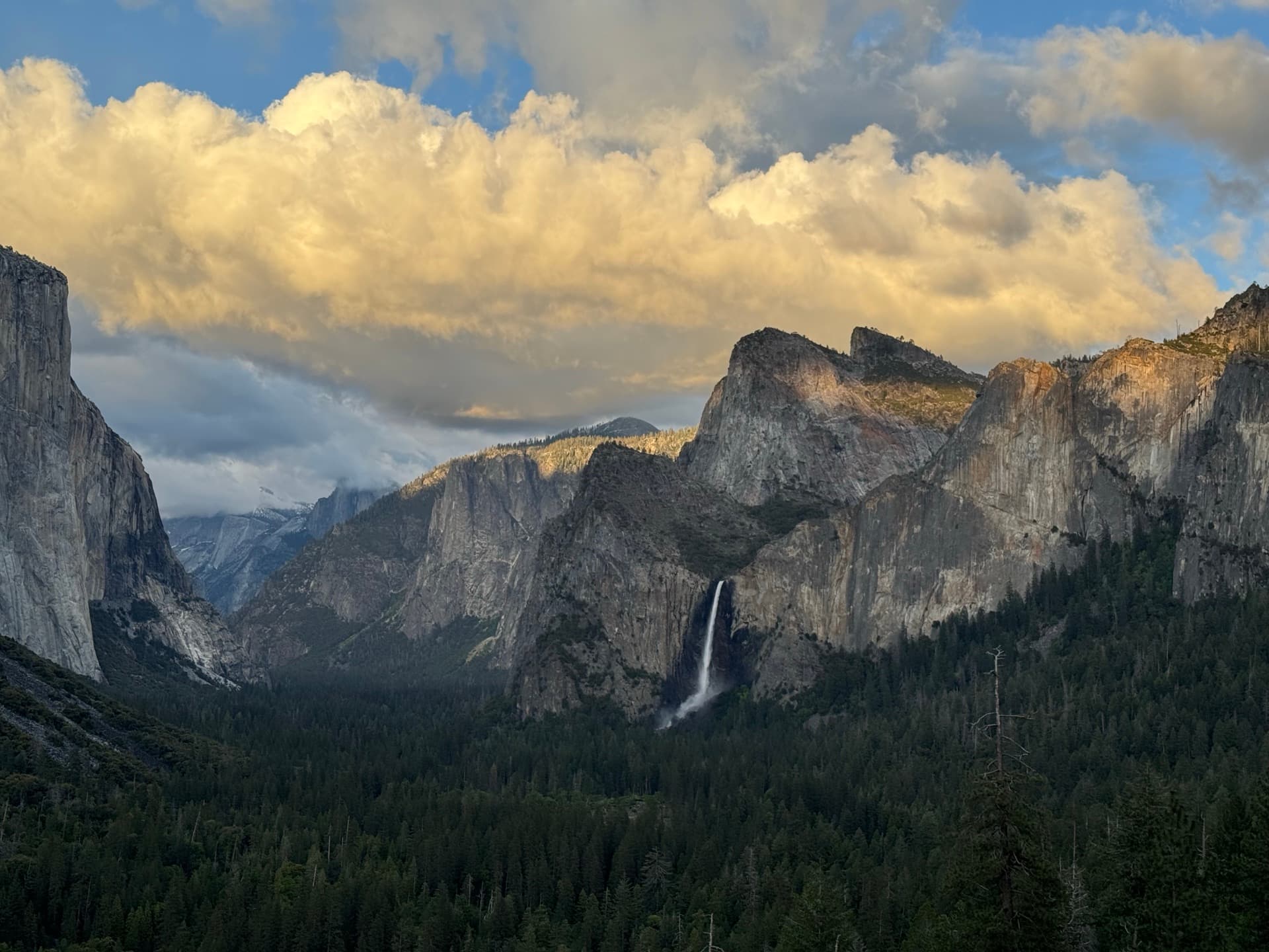 A waterfall between tall granite cliffs under golden clouds